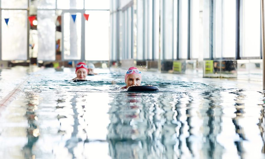 Active woman in swimwear swimming after black rubber ring while holding it by both hands